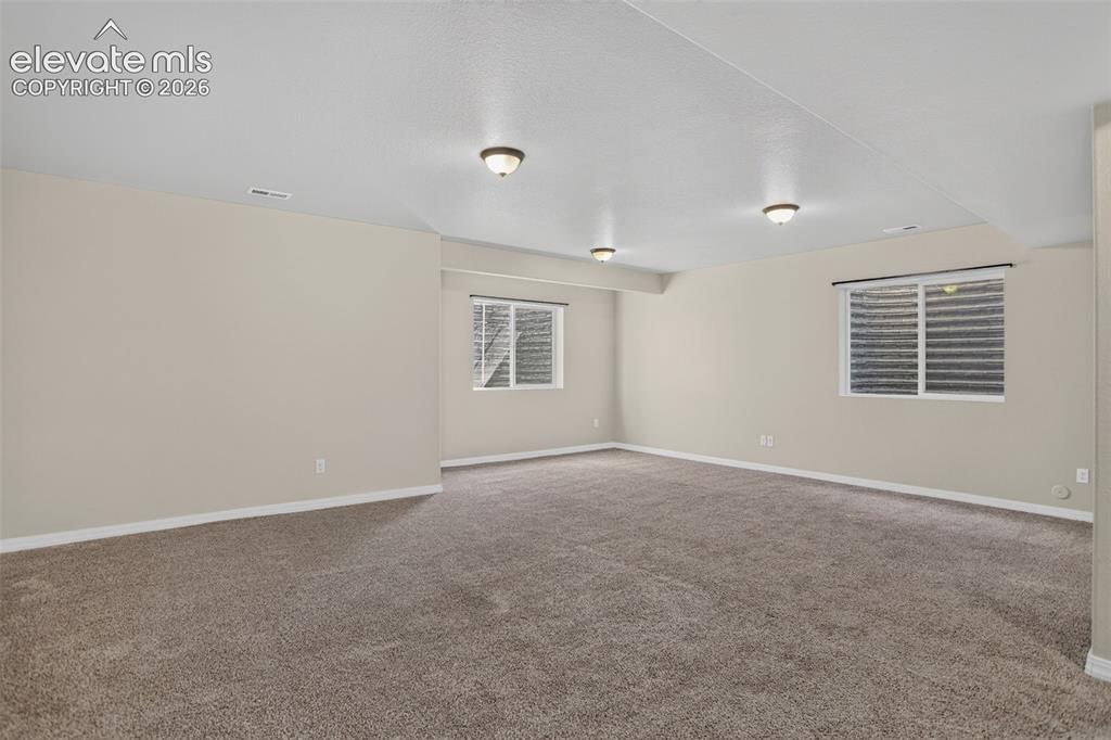 Image 34 of 50: Carpeted living space featuring recessed lighting and multiple windows with