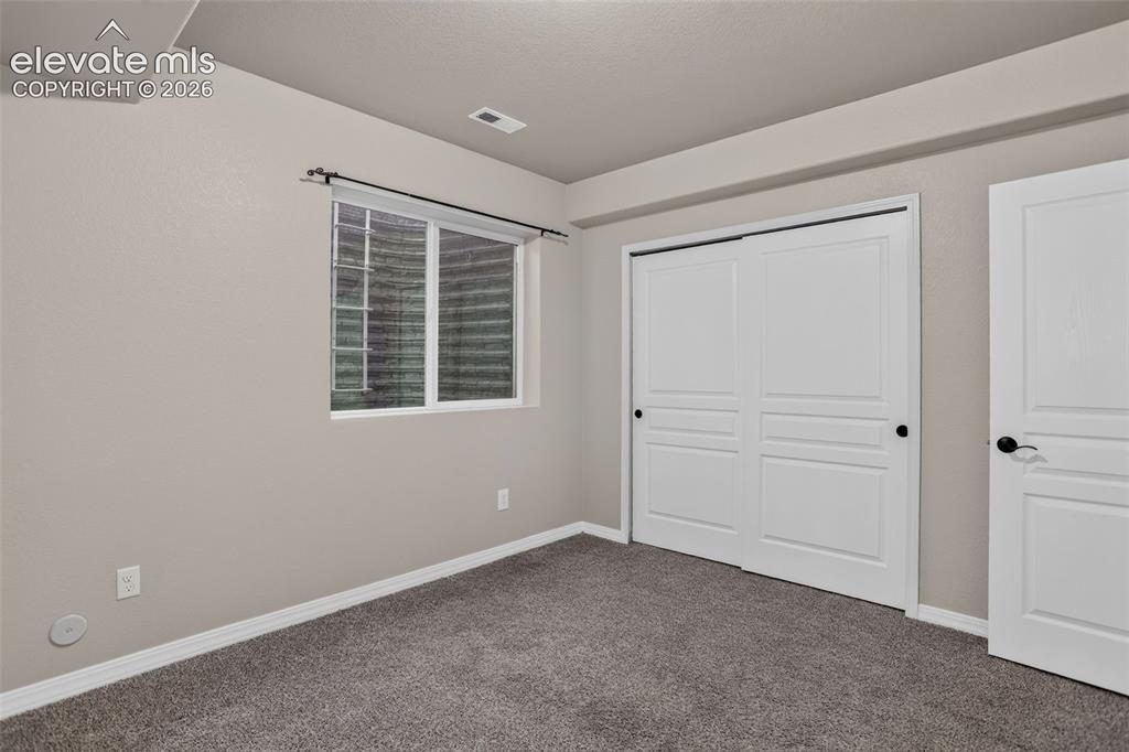 Image 38 of 50: Neutral wall paint, gray carpet, white trim, sliding closet doors with blac