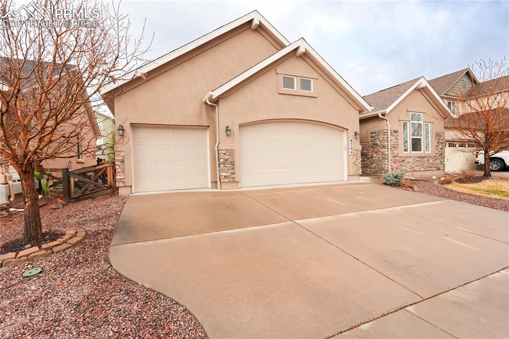 Image 42 of 44: View of front facade with stucco siding, concrete driveway, a garage, and s