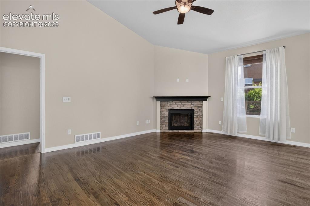 Image 8 of 50: Vaulted ceiling, wood-finish flooring, corner fireplace with stone surround