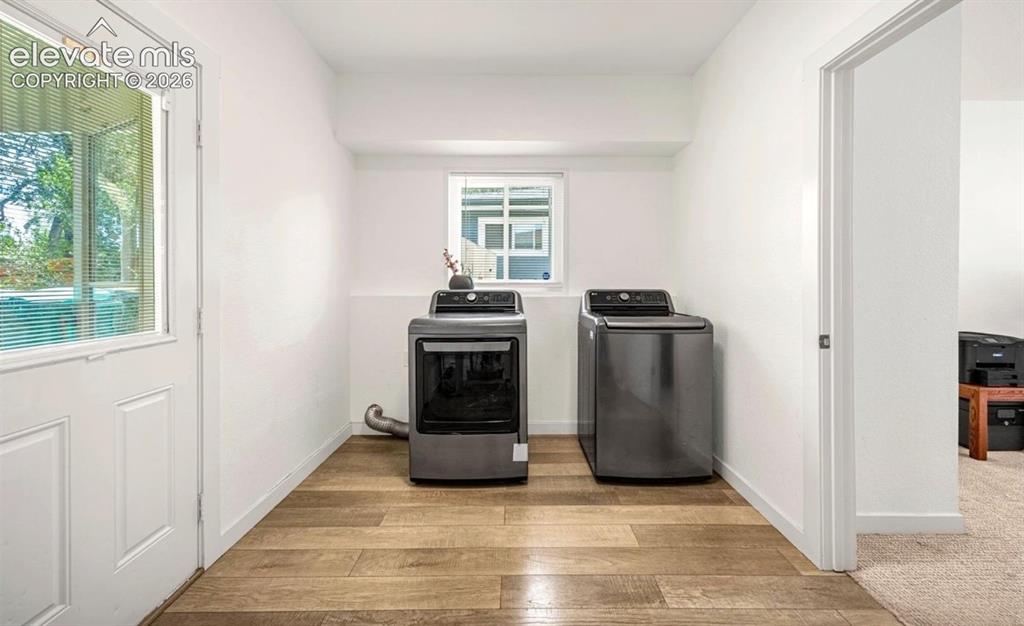 Image 10 of 11: Wood-finish flooring, white paneled door with glass insert, white walls, an