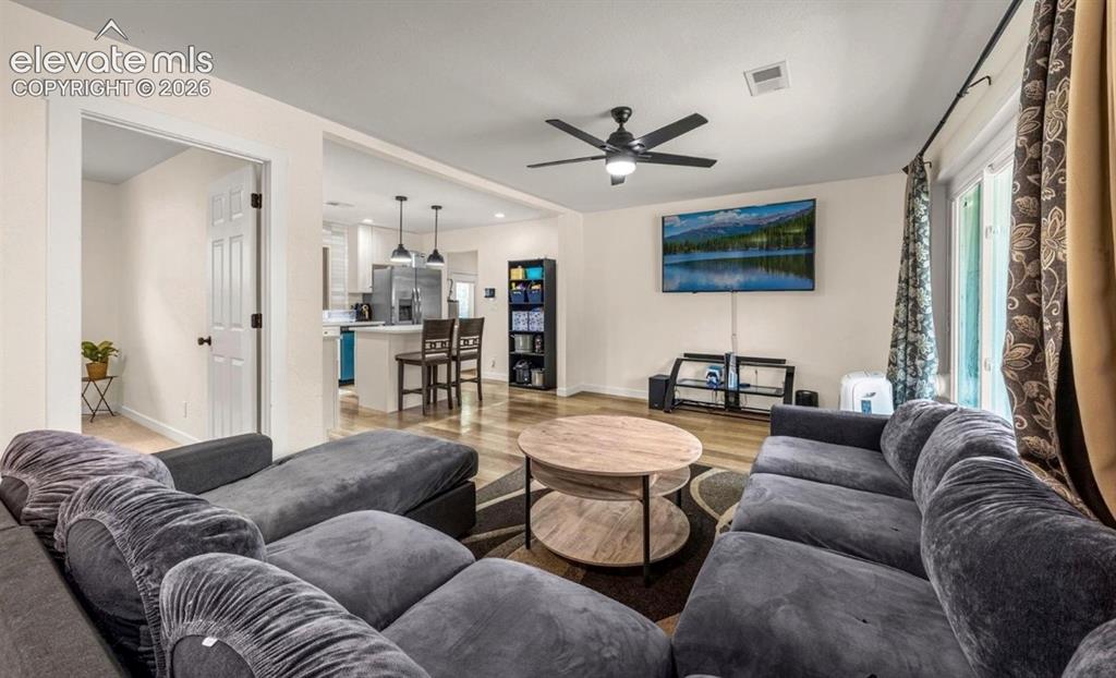 Image 2 of 11: Open-concept living area with wood-finish flooring, a ceiling fan, and slid