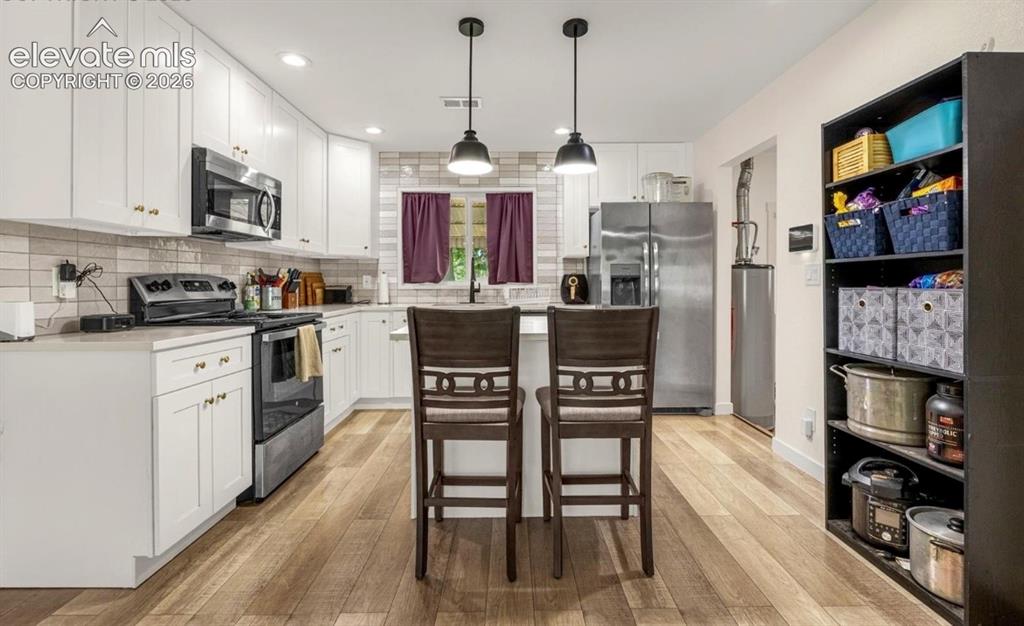 Image 4 of 11: Kitchen featuring light wood-finish flooring, white cabinetry, stainless st