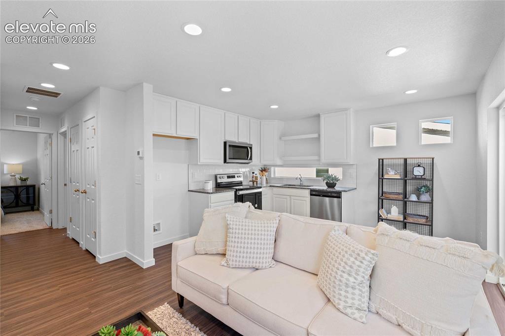 Image 10 of 25: White kitchen cabinetry, stainless steel appliances, dark countertops, rece