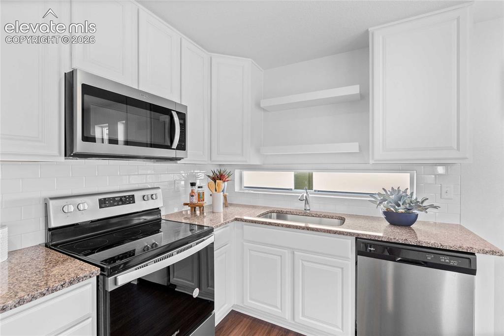 Image 12 of 25: Kitchen featuring white cabinetry, granite-style countertops, stainless ste