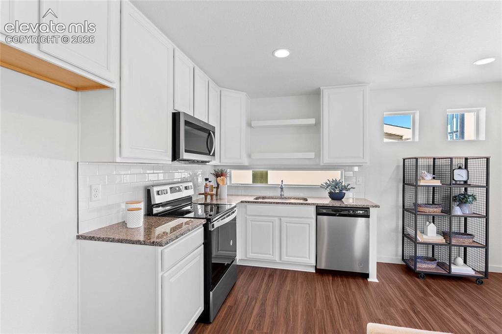 Image 13 of 25: White shaker cabinetry, dark wood-finish flooring, undermount sink, stainle