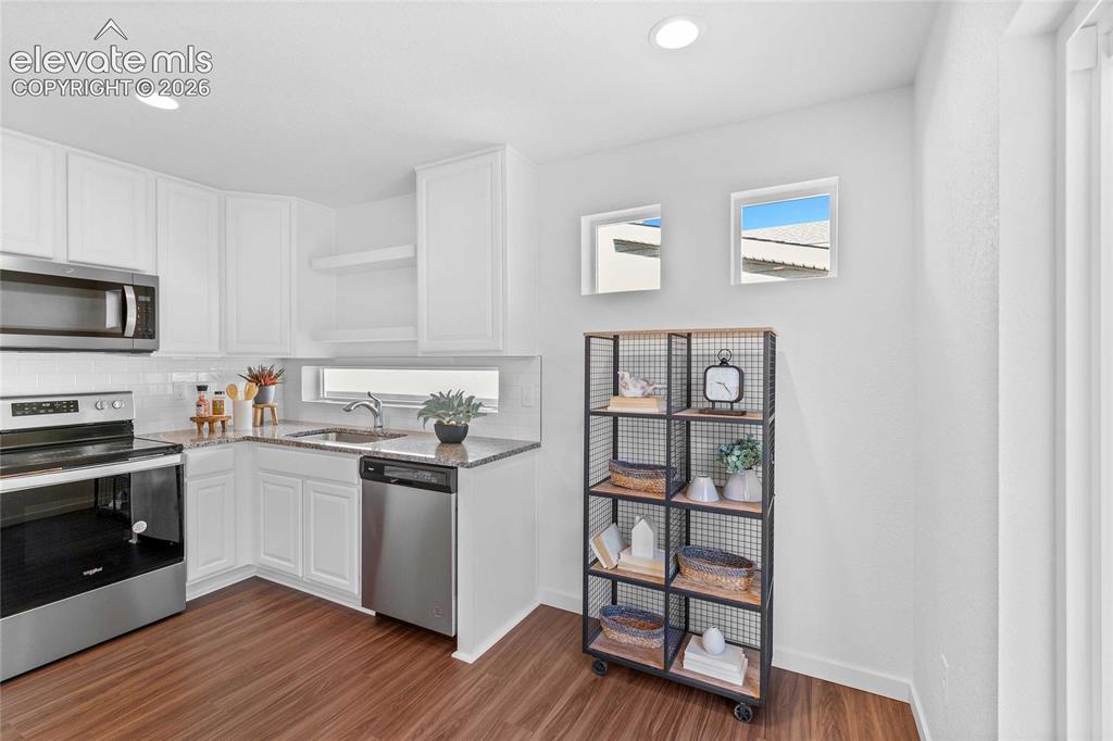Image 14 of 25: White cabinetry, stainless steel appliances, wood-finish flooring, recessed