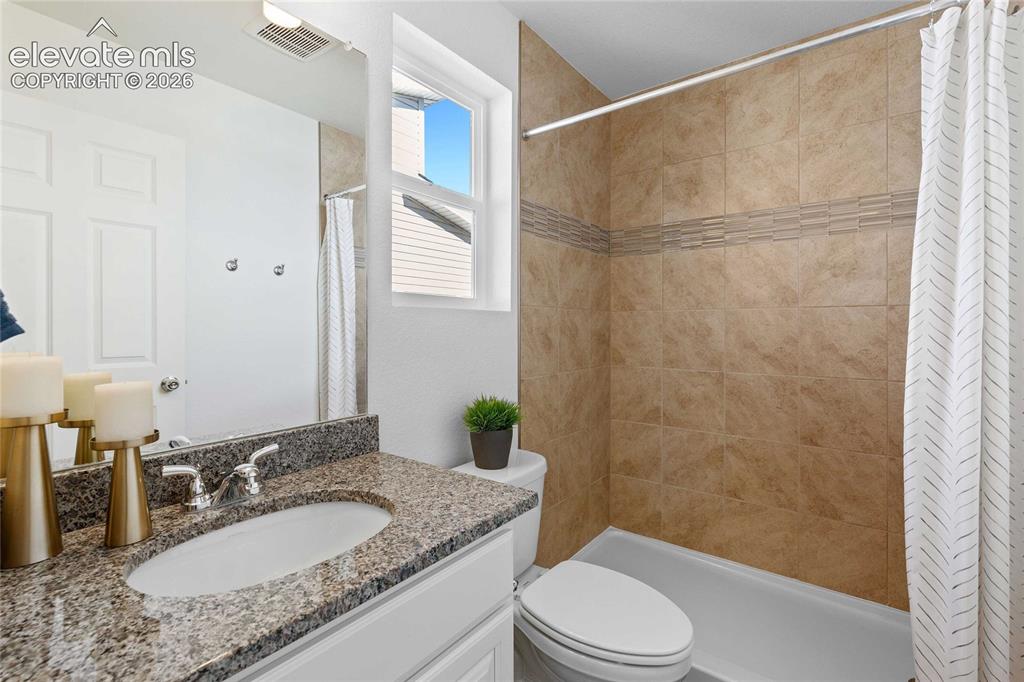 Image 17 of 25: Bathroom featuring a granite-finish vanity countertop, single basin sink, a