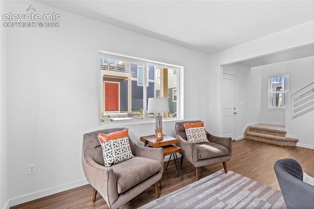 Image 2 of 25: Hardwood-look flooring, white interior walls, and a modern staircase with o