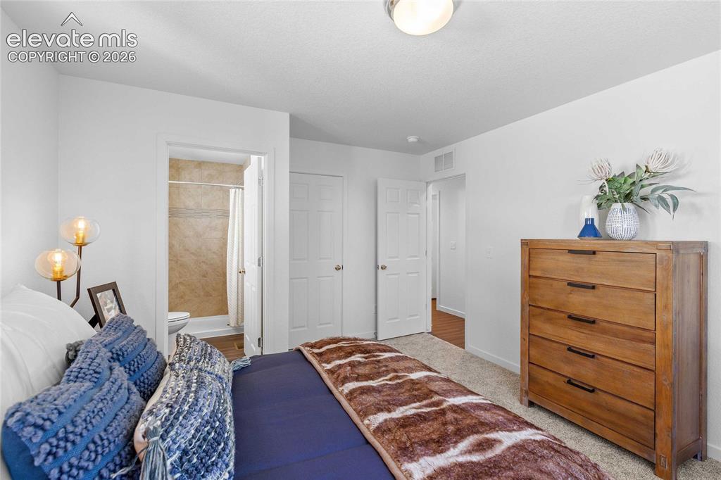 Image 20 of 25: Carpeted flooring, white interior doors, and a bathroom with a tiled shower