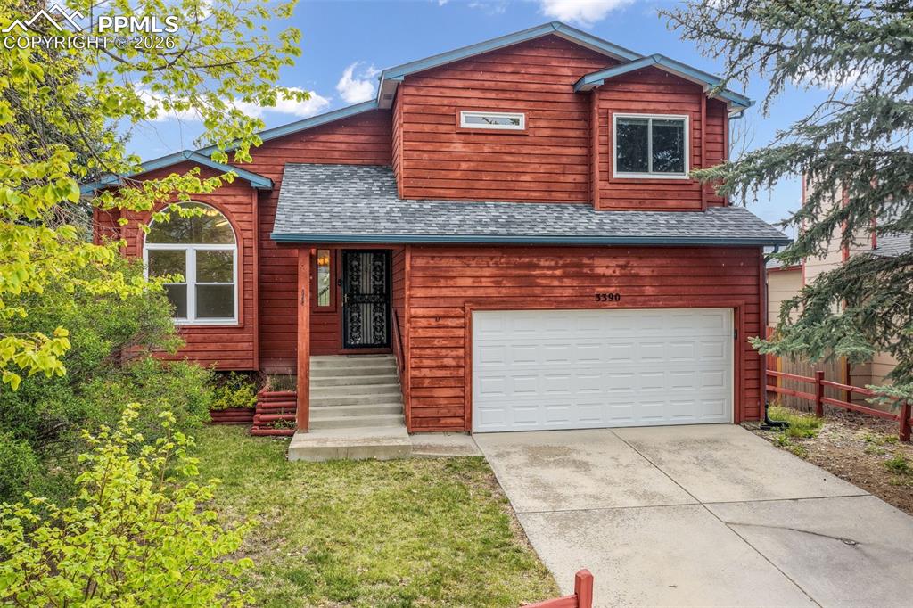 Caption: Two-story residence featuring a red wood-panel exterior, an attached two-car garage, and a grey shin