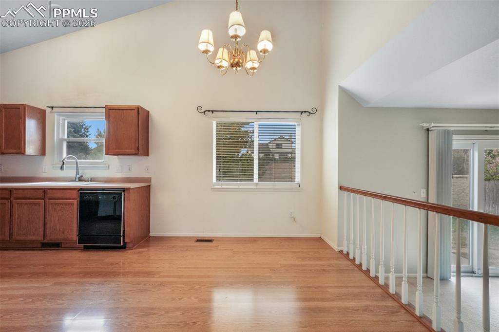 Image 12 of 45: Kitchen and living area featuring wood-finish flooring, vaulted ceilings, a