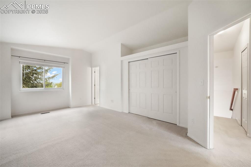 Image 24 of 45: Spacious interior room with light-toned carpeting and white walls