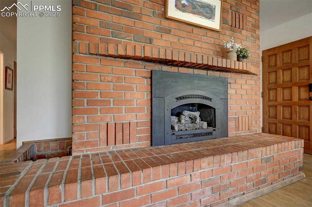 Image 11 of 50: Gas log fireplace with commanding floor to ceiling brick surround and raise