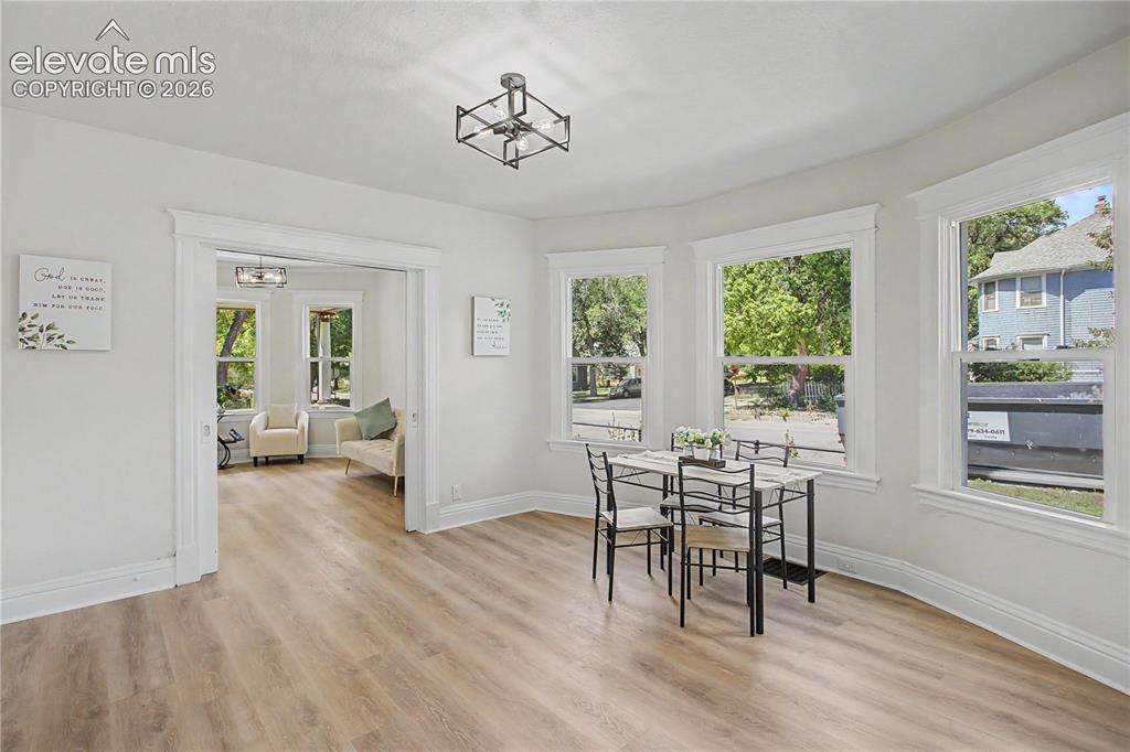 Image 10 of 35: Light wood-finish flooring throughout, multiple large windows with white tr