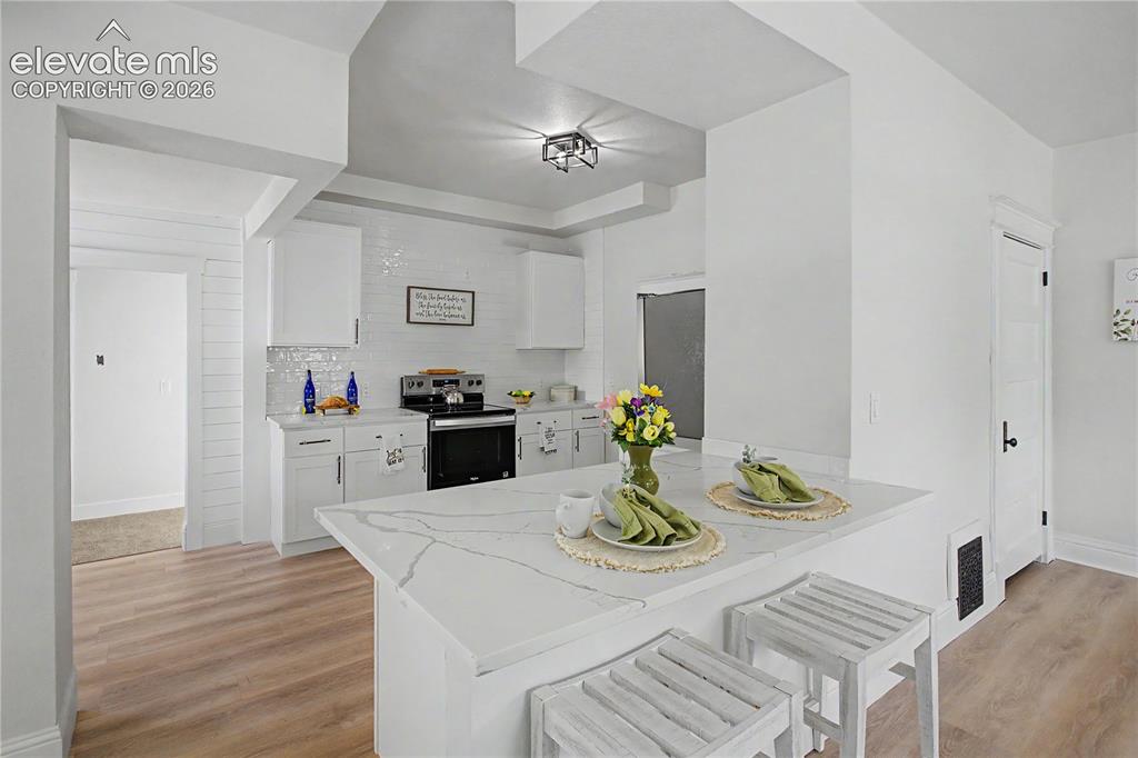 Image 11 of 35: Modern kitchen with white cabinetry and a white subway tile backsplash