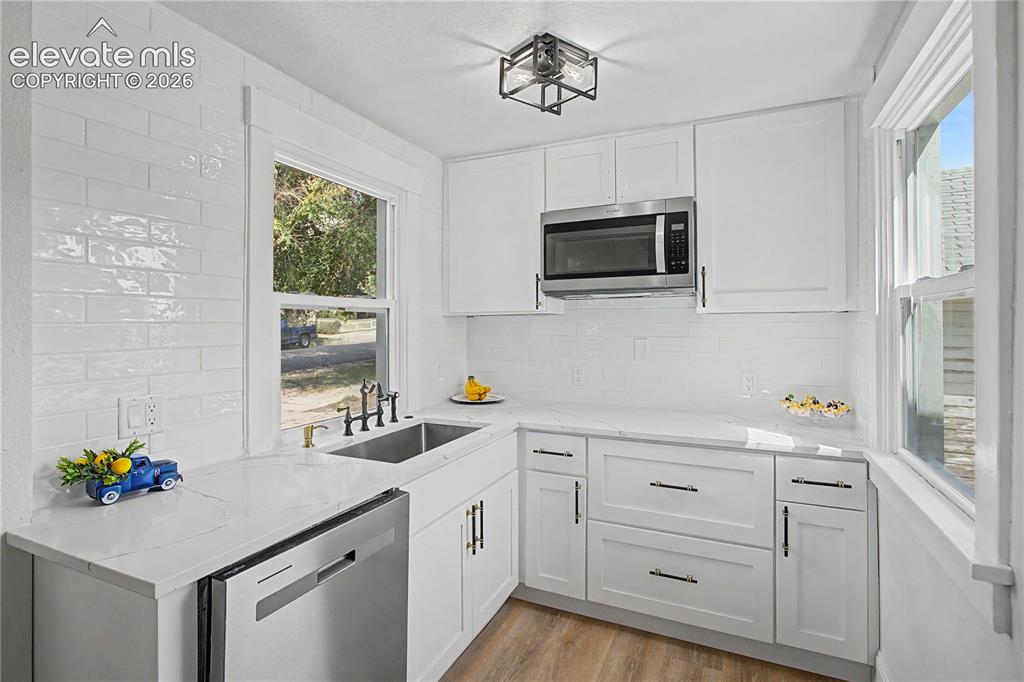 Image 12 of 35: White shaker cabinetry, stainless steel microwave, integrated sink with mat