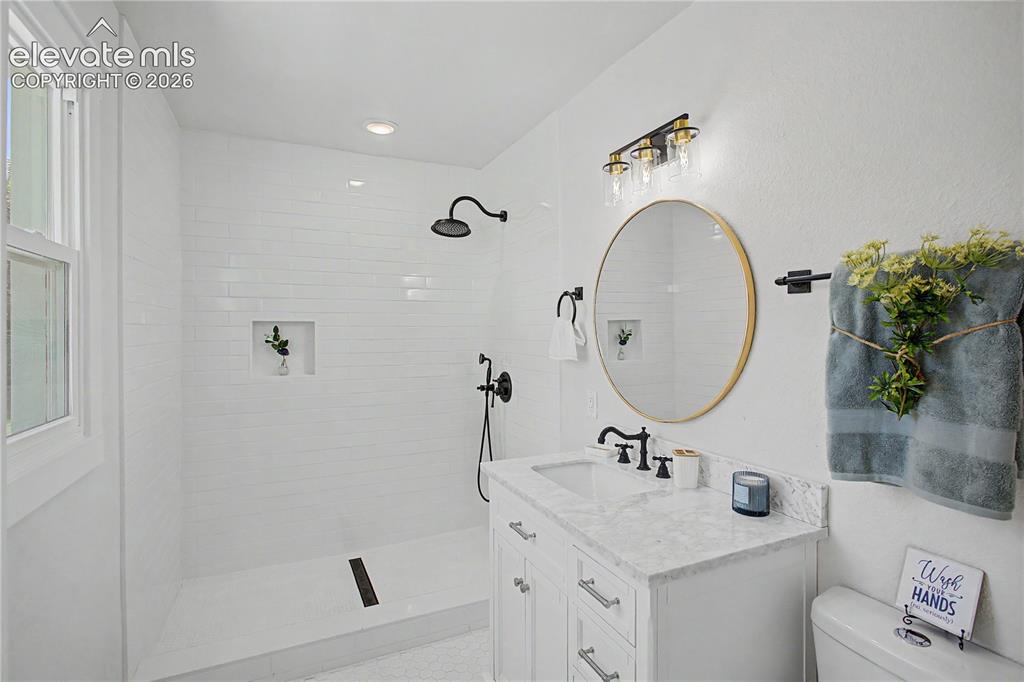 Image 16 of 35: Bright bathroom with a walk-in shower featuring subway tile, a shower niche