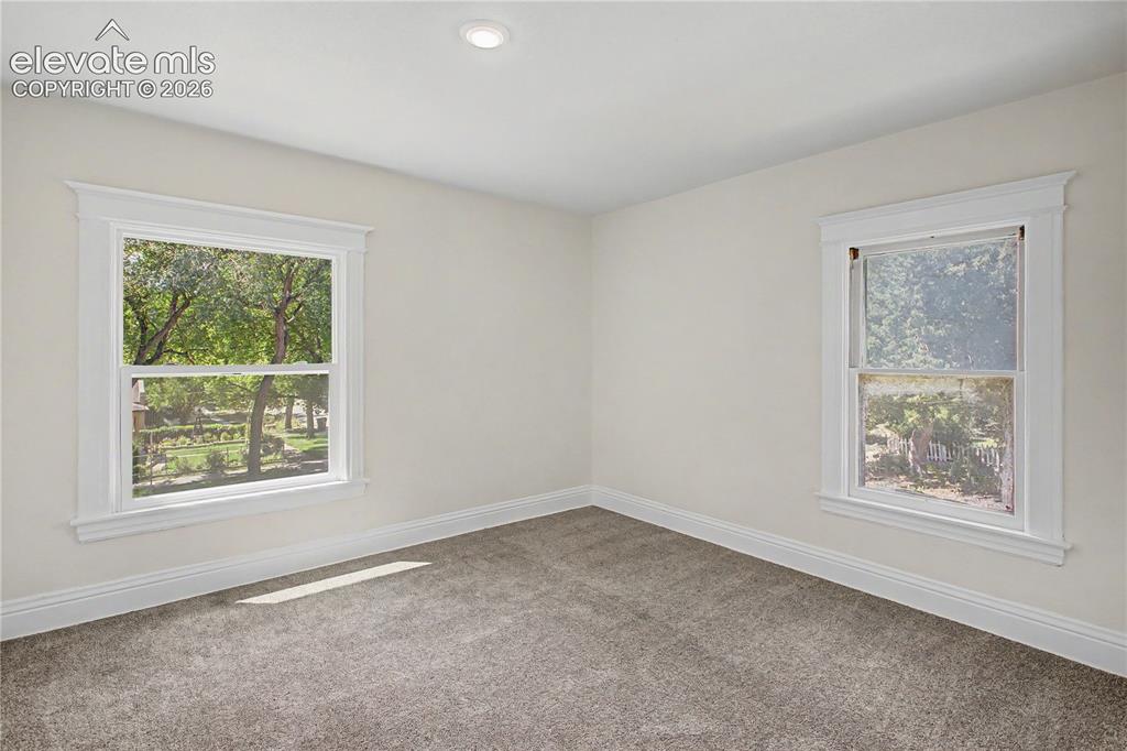 Image 24 of 35: Recessed lighting, plush carpeting, bright white walls, and two large windo