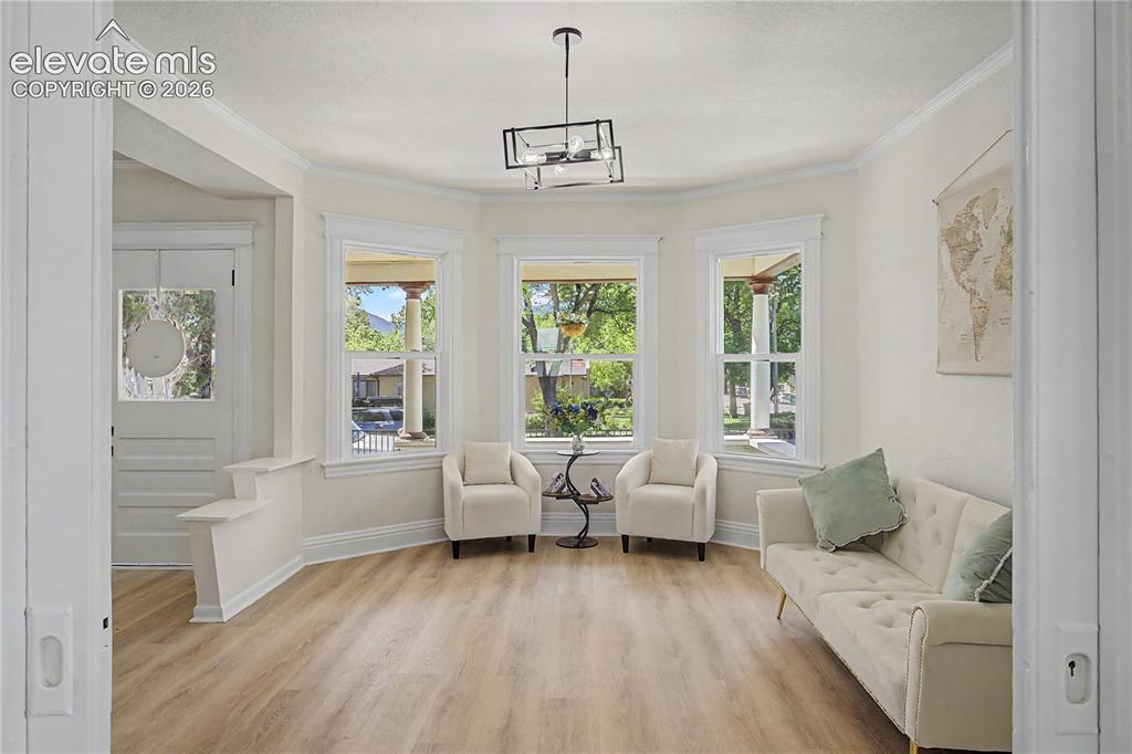 Image 7 of 35: Bay window design with three large windows, wood-finish flooring, crown mol