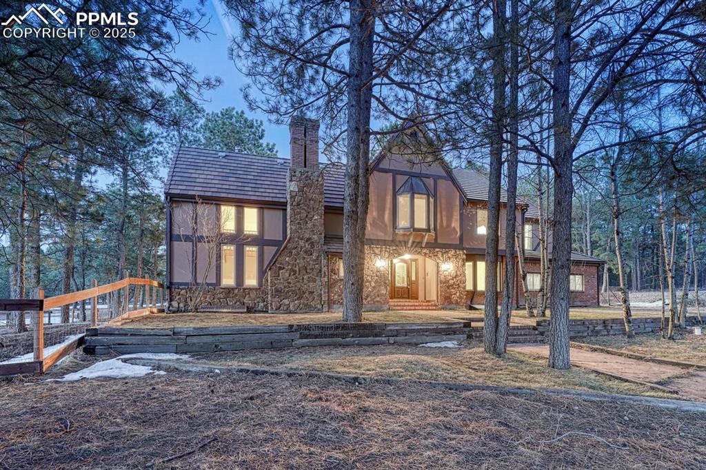 Caption: Back of property featuring stone siding and a chimney