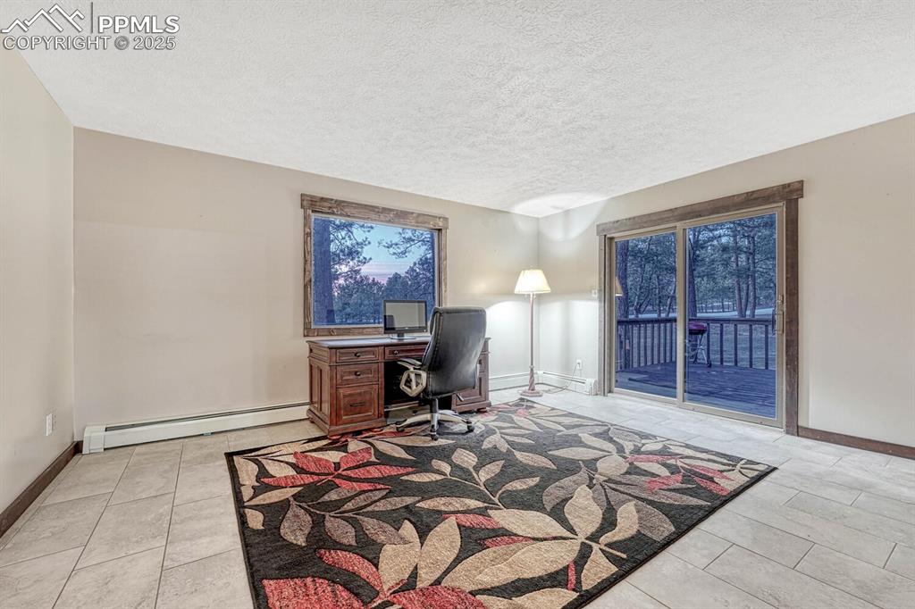 Image 15 of 47: Home office featuring light tile patterned floors, a baseboard radiator, ba