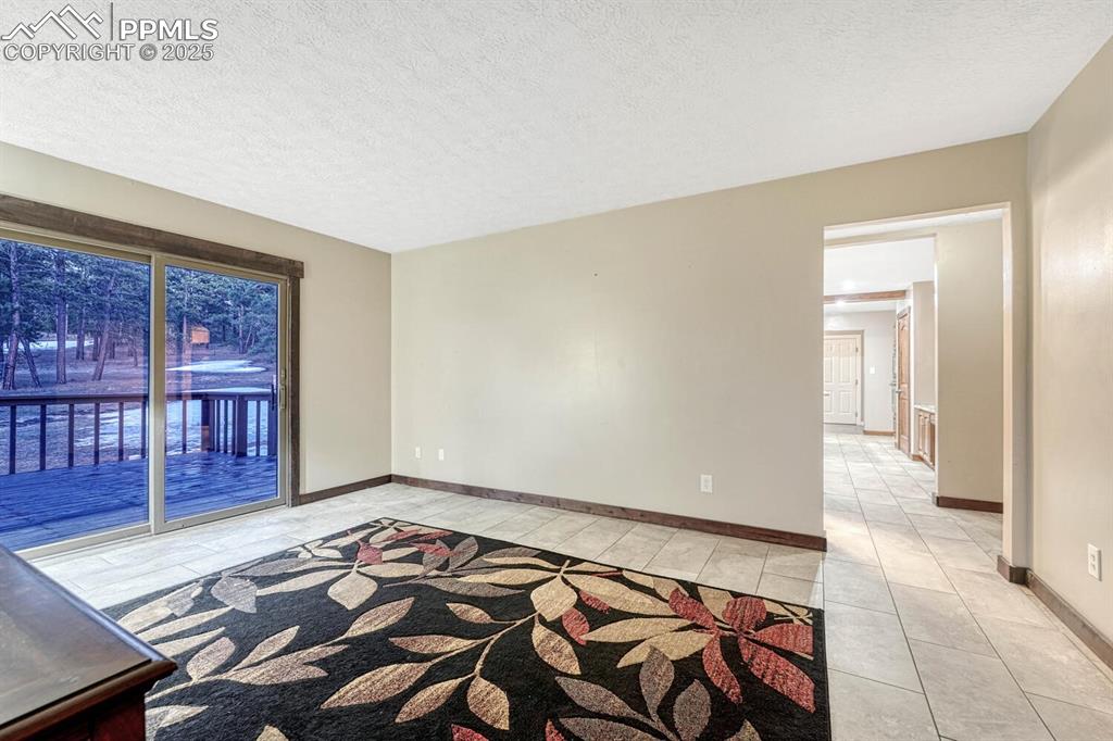 Image 16 of 47: Unfurnished room with light tile patterned floors, baseboards, and a textur