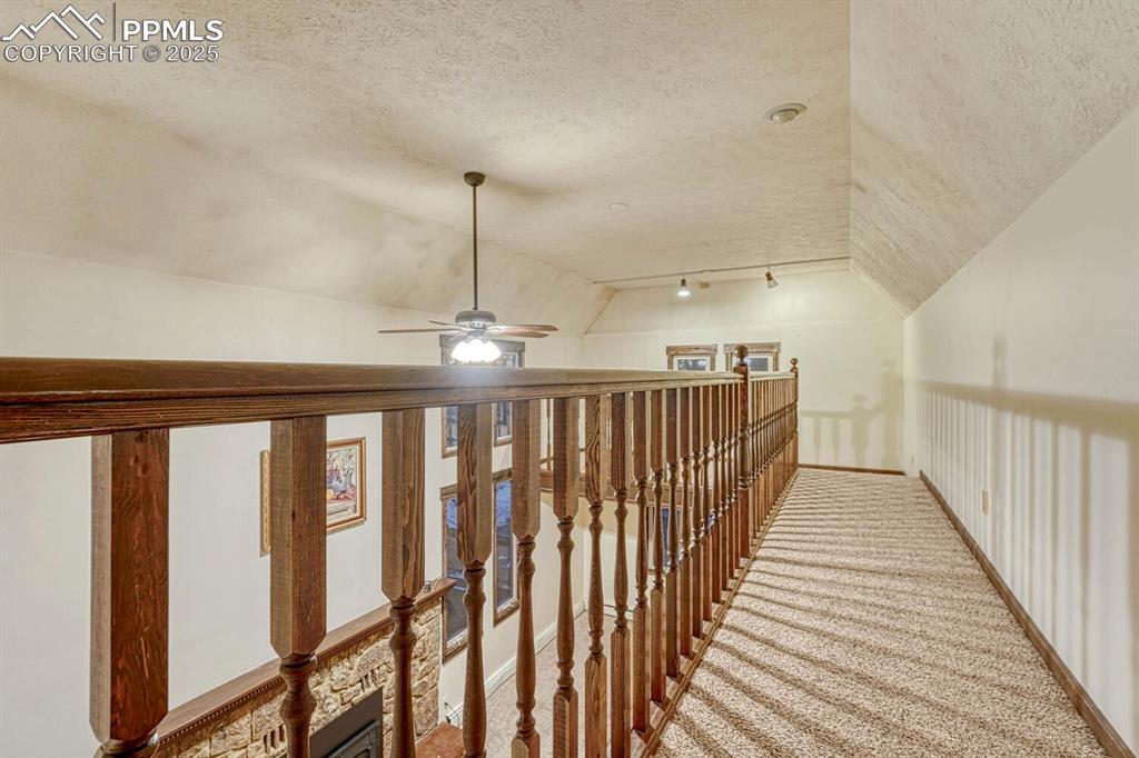 Image 18 of 47: Corridor with carpet floors, lofted ceiling, and a textured ceiling