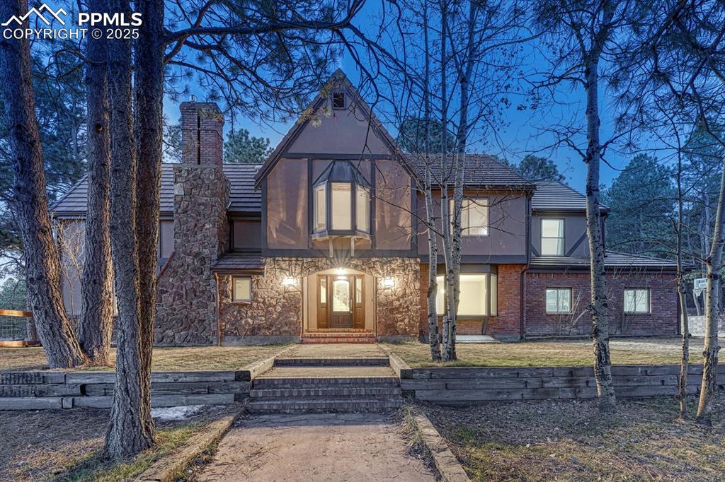 Image 2 of 47: Tudor-style house featuring stucco siding and a chimney