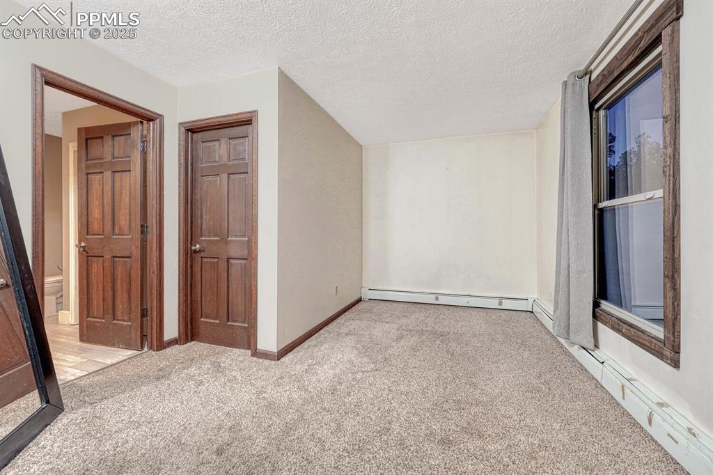 Image 20 of 47: Additional living space featuring a baseboard radiator, a textured ceiling,