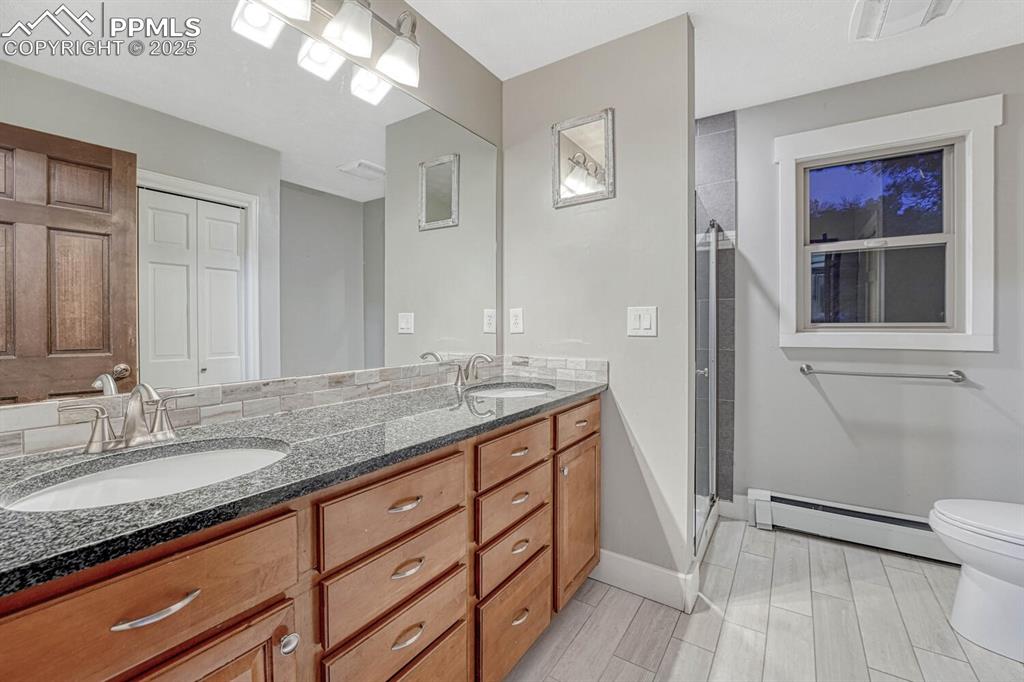 Image 22 of 47: Bathroom with a sink, baseboards, toilet, and baseboard heating