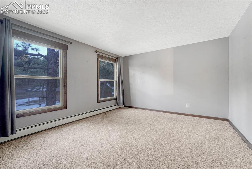 Image 24 of 47: Spare room with a textured ceiling, a baseboard heating unit, baseboards, a