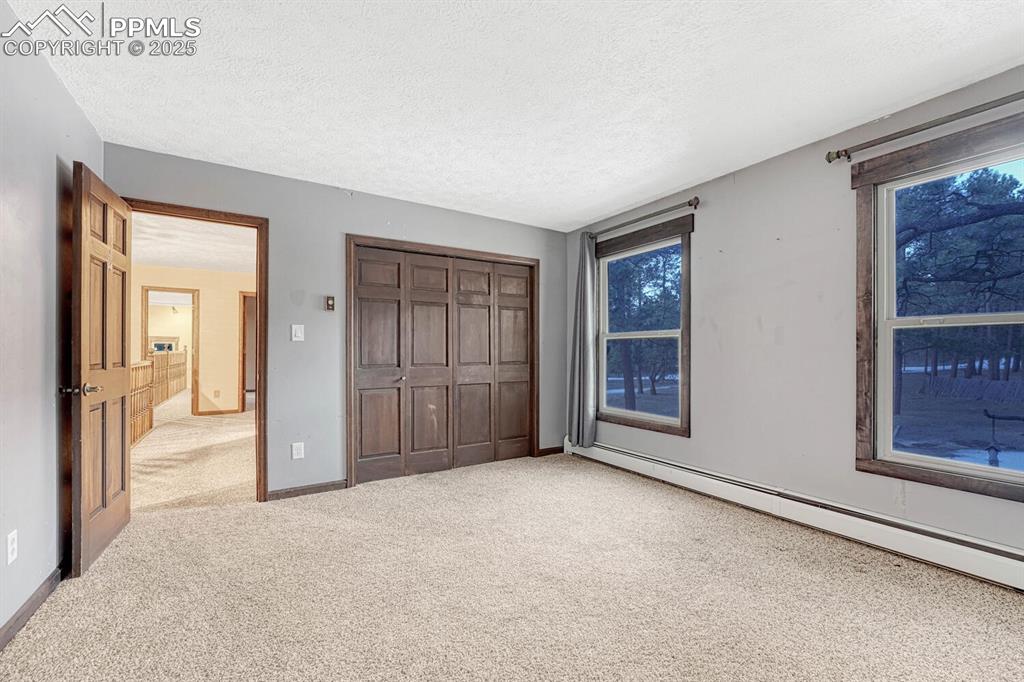 Image 26 of 47: Unfurnished bedroom with a textured ceiling, a closet, carpet flooring, a b