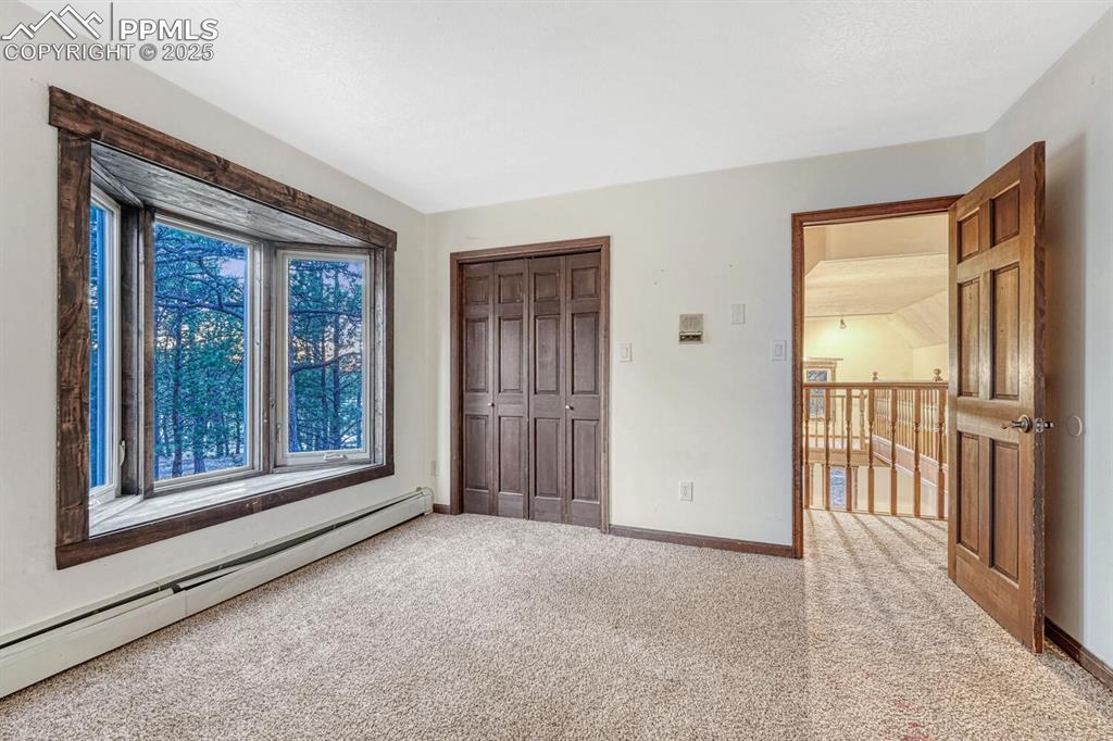 Image 27 of 47: Unfurnished bedroom with a closet, a baseboard heating unit, baseboards, an