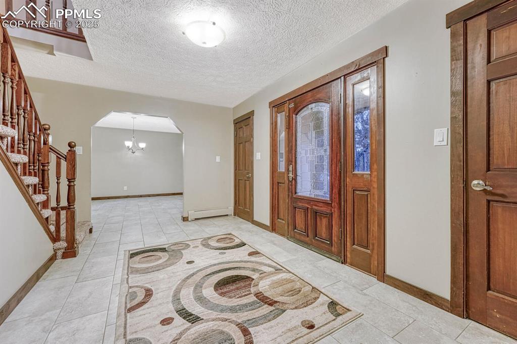 Image 6 of 47: Entryway with baseboard heating, arched walkways, baseboards, and a texture