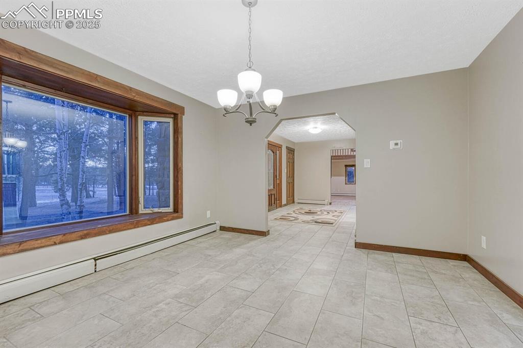 Image 8 of 47: Spare room with a chandelier, a baseboard radiator, baseboards, and arched
