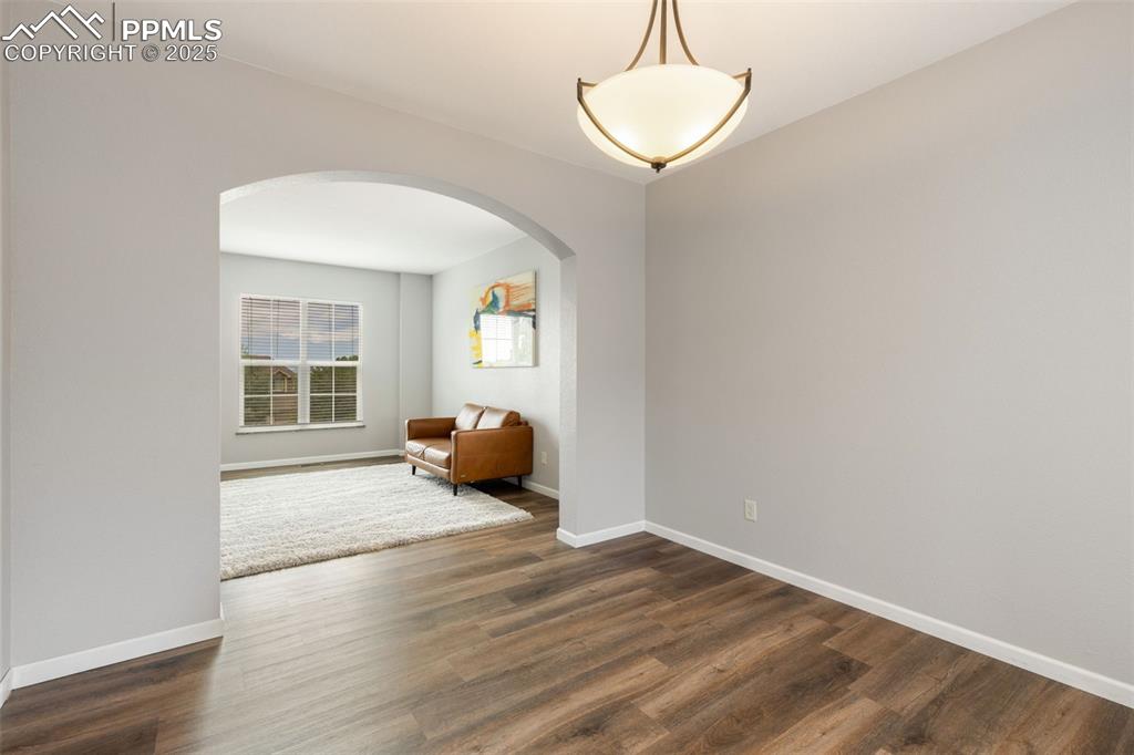 Image 10 of 41: Sitting room with arched walkways and dark wood-style floors