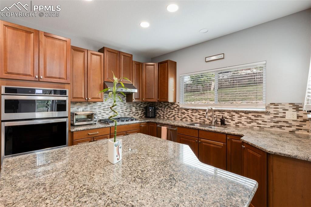 Image 11 of 41: Kitchen featuring stainless steel appliances, backsplash, light stone count