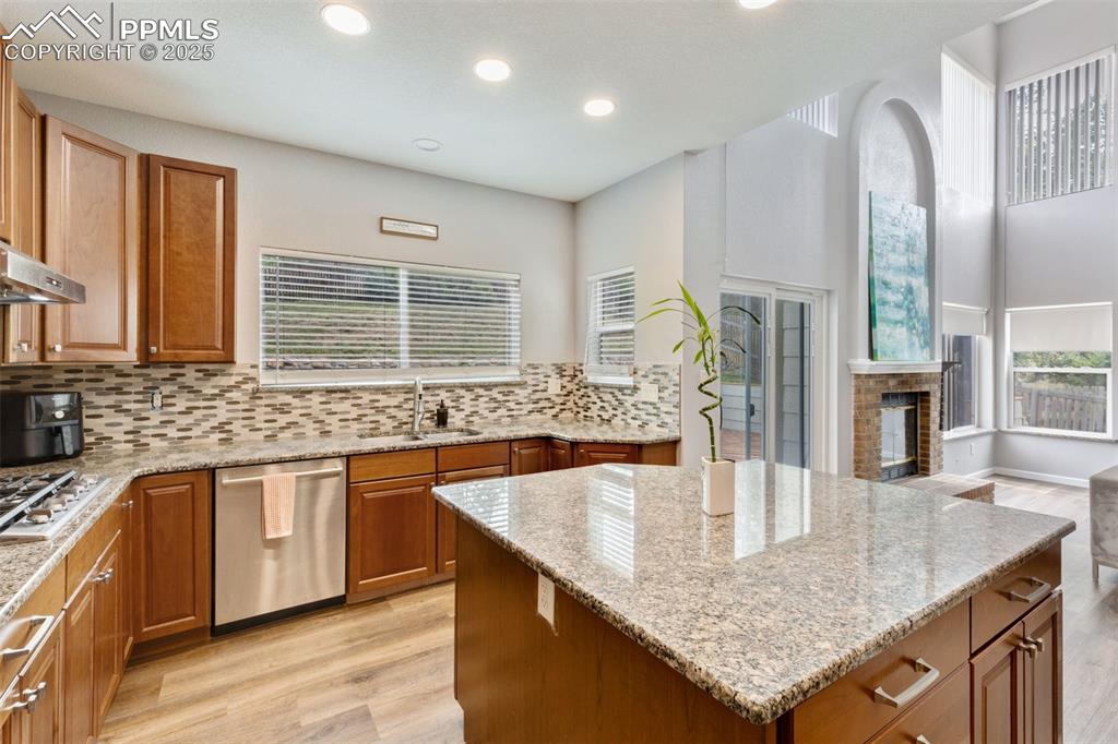 Image 12 of 41: Kitchen featuring tasteful backsplash, light wood-style floors, light stone