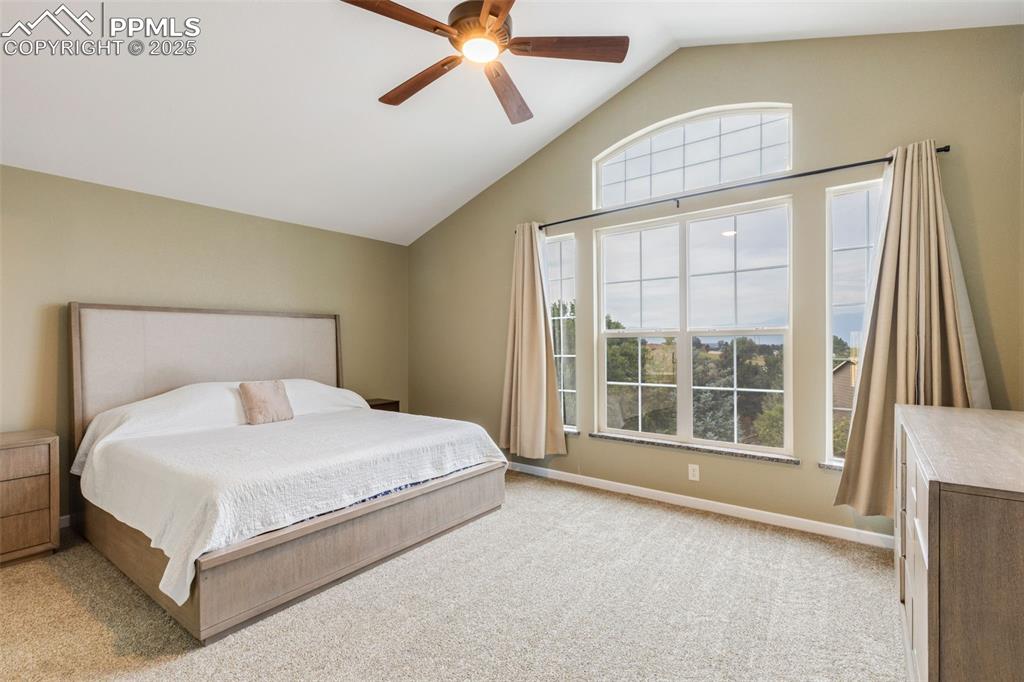 Image 18 of 41: Bedroom with light carpet, a ceiling fan, and high vaulted ceiling