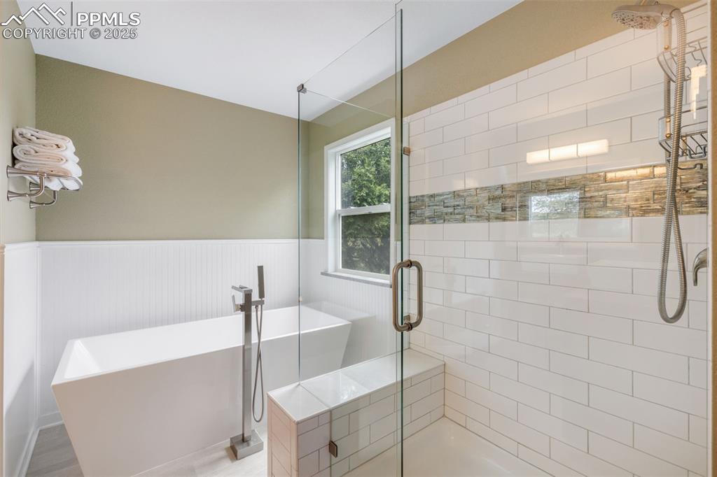Image 21 of 41: Full bathroom with wainscoting, a shower stall, and a freestanding tub