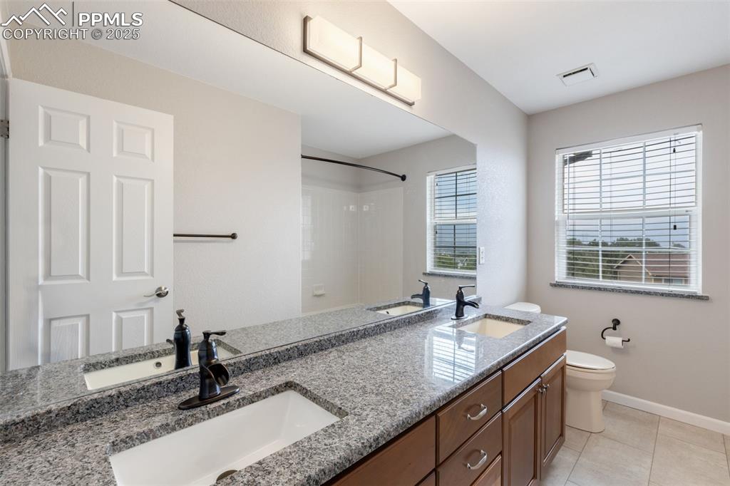 Image 26 of 41: Bathroom featuring double vanity, a shower, and tile patterned floors
