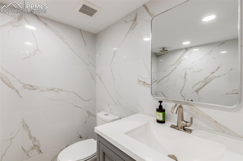 Image 32 of 41: Bathroom featuring vanity, stone wall, and a marble finish shower