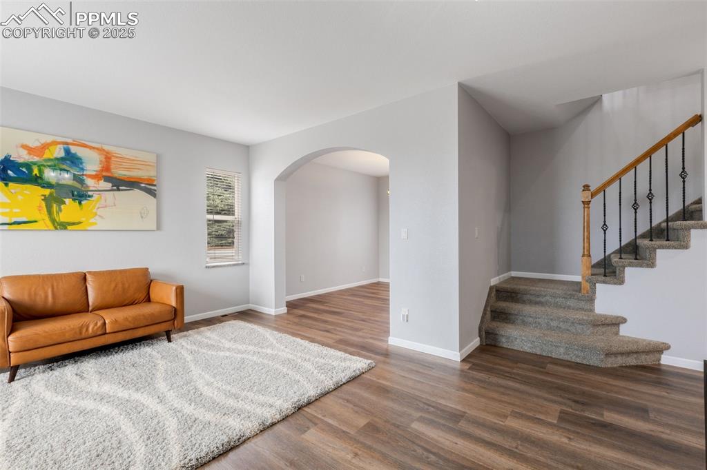 Image 6 of 41: Living room featuring arched walkways, wood finished floors, and stairway