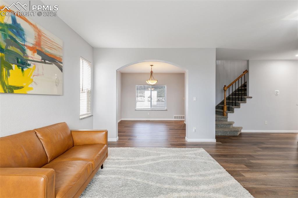 Image 7 of 41: Living area with arched walkways, wood finished floors, and stairs