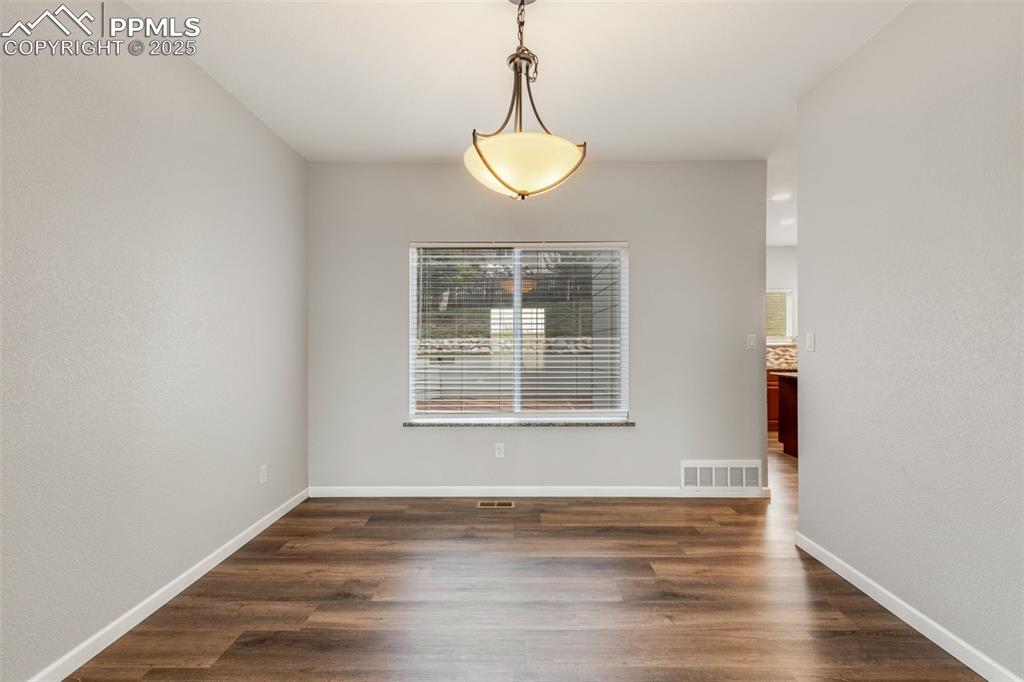 Image 9 of 41: Unfurnished dining area with dark wood-style flooring and baseboards