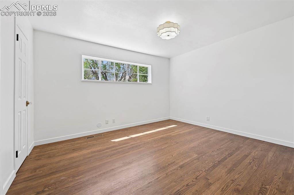 Image 10 of 21: Spacious room featuring wood-finish flooring, white walls, and a multi-pane