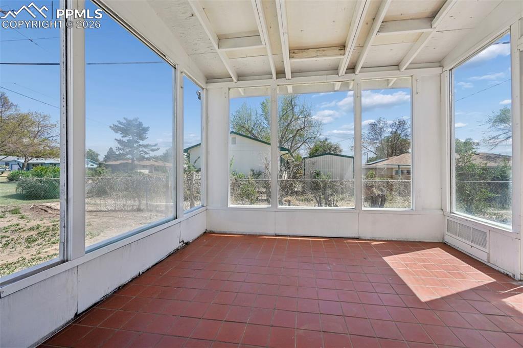 Image 15 of 21: Enclosed sunroom featuring expansive windows and terra cotta tile flooring