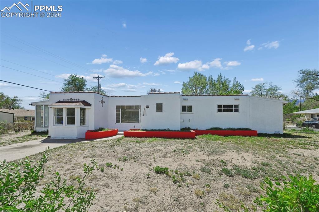 Image 19 of 21: Single-story stucco exterior featuring a bay window, a flat roofline, and r