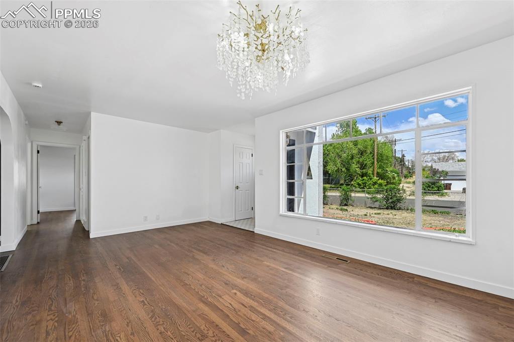 Image 7 of 21: Spacious living room with wood flooring and a large picture window. 